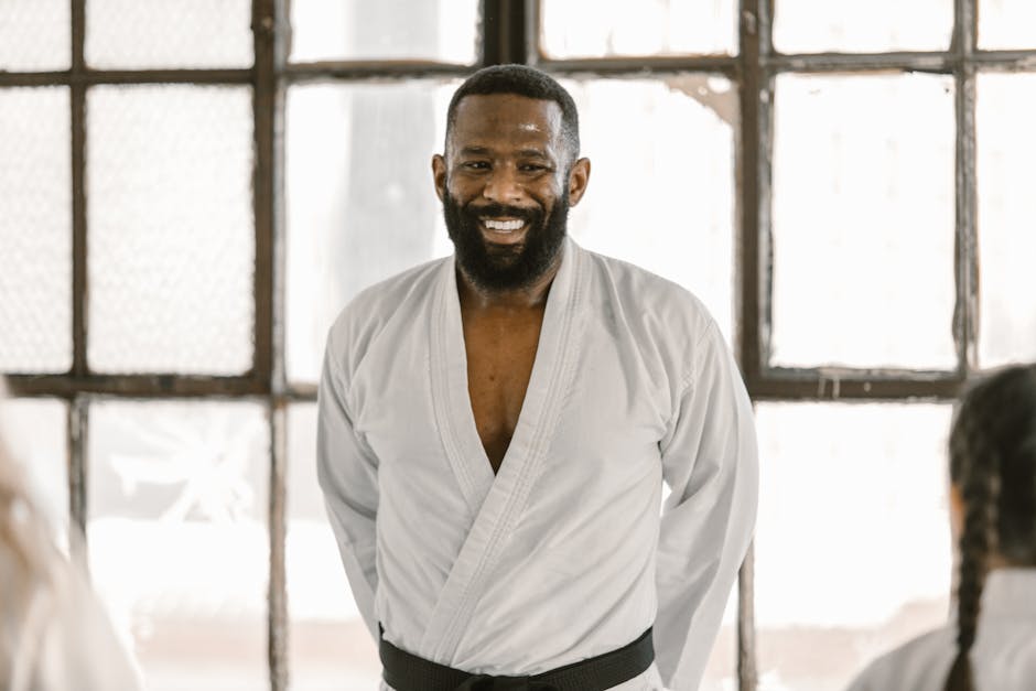 A confident martial arts instructor wearing a black belt in the dojo, exuding positivity.